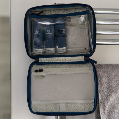 Three blue silicone travel bottles inside the clear toiletry pouch. The pouch is attached inside the OneNine5, Havelock Blue wash bag, using the hanging hook, in the bathroom.