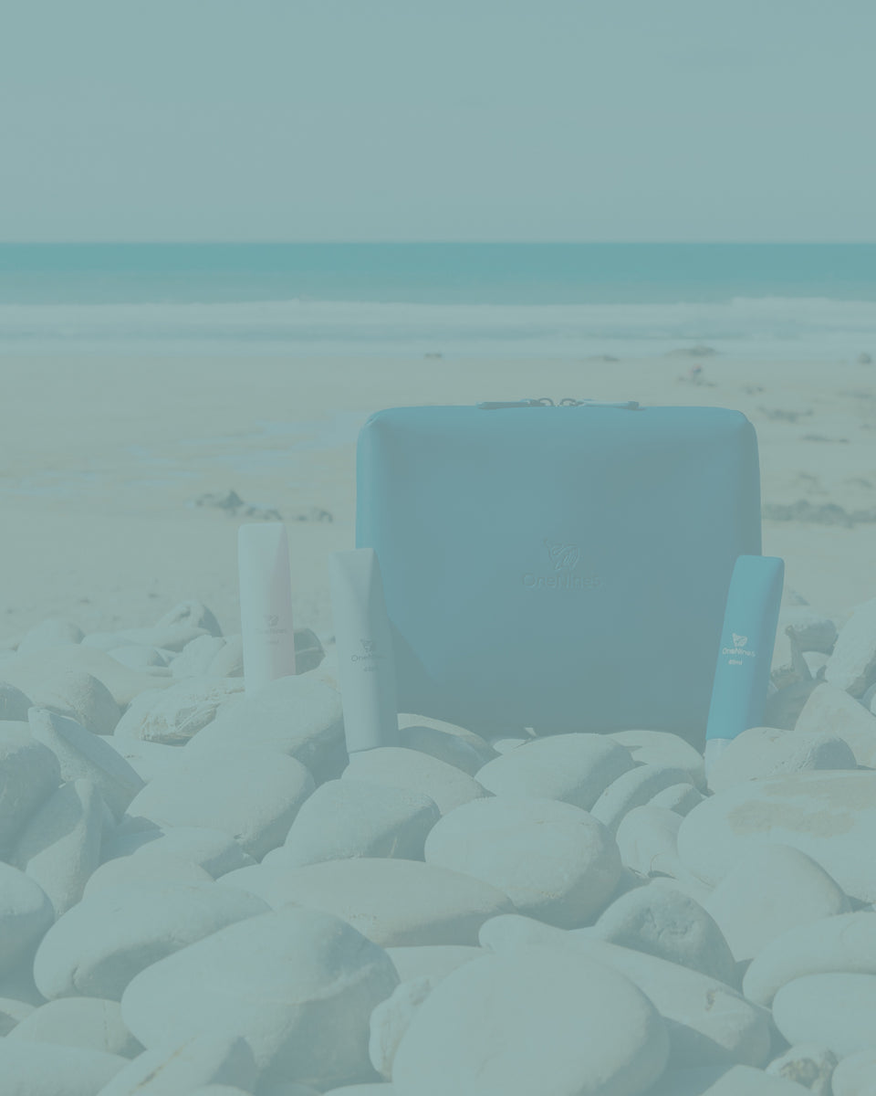 A banner image of the Havelock Blue Eco-Conscious Wash Bag & refillable silicone bottles on a beach